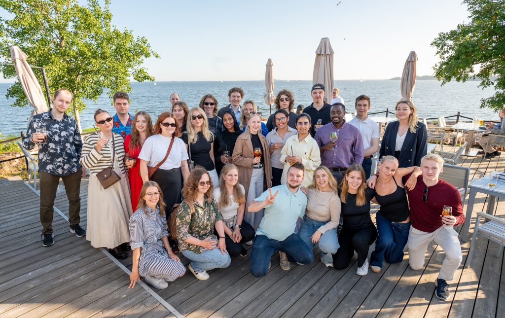 Joukko harjoittelijoita yhteiskuvassa, meri taustalla.